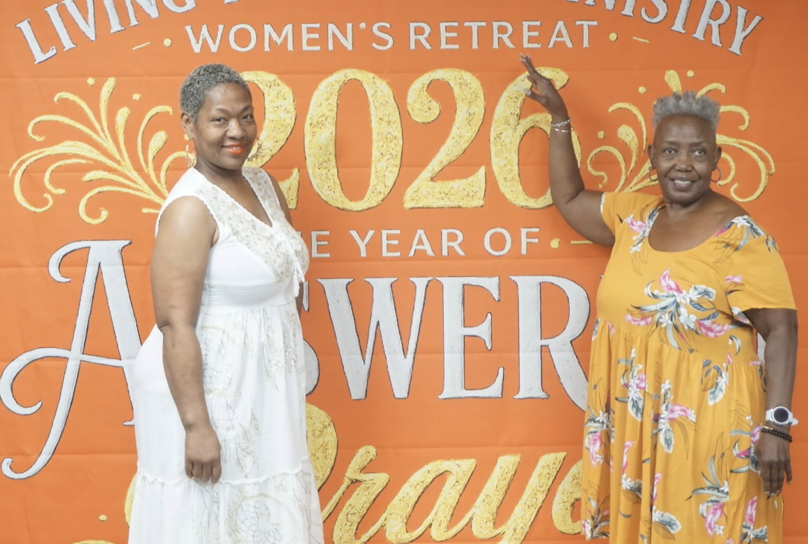 Two women posing at the Women's Retreat backdrop